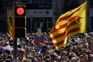People hold an 'Estelada' (Catalan pro-independence flag) and a placard depecting Spanish Prime Minister Mariano Rajoy man during a protest in Barcelona on September 20, 2017.  Thousands took to the streets of Barcelona as Spanish police detained 13 Catalan government officials in a crackdown ahead of an independence referendum which Madrid says is illegal. With tensions mounting, separatist organisations called for more people to protest as leaders in the northeastern region pressed ahead with preparations for the October 1 vote despite Madrid's ban and a court ruling deeming it unconstitutional. / AFP PHOTO / LLUIS GENE